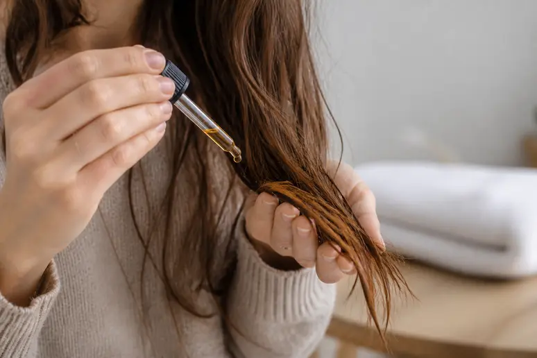 Application de l'huile de jojoba sur les pointes de cheveux pour hydratation et brillance.