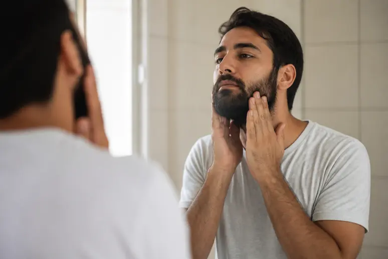 Homme appliquant l'huile de ricin pour la barbe, soin naturel et efficace.
