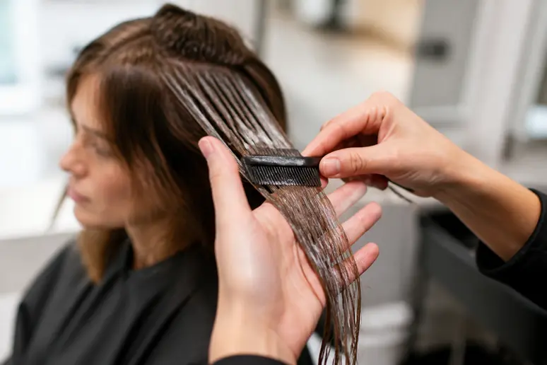 Coiffeuse appliquée réalisant un lissage indien sur une cliente dans un salon parisien, focus sur la durée du soin.