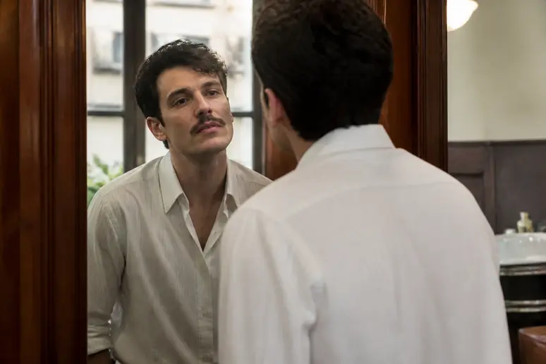 Un homme arbore une élégante moustache fine dans un barbershop parisien, reflet d'une beauté soignée.