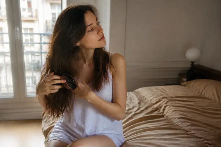 Femme parisienne aux cheveux ondulés rangeant ses boucles le matin pour protéger ses boucles la nuit.