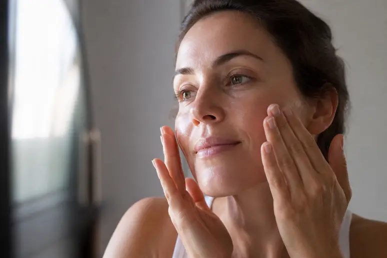 Application d'un sérum hydratant sur le visage, améliorant l'apparence des ridules de déshydratation.