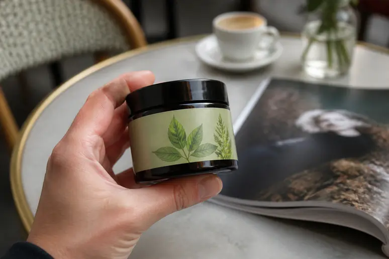 Une main examine une wax-cire-cheveux naturelle, prête pour une coiffure parfaite.
