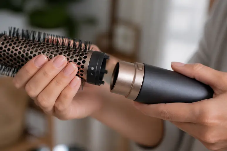 Mains assemblant un embout sur la brosse soufflante babyliss air style 1000 dans une pièce lumineuse