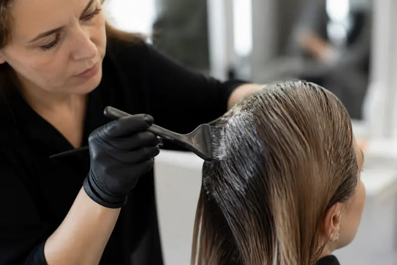 Application d'un soin neutralisant sur des cheveux blond foncé cendré en salon