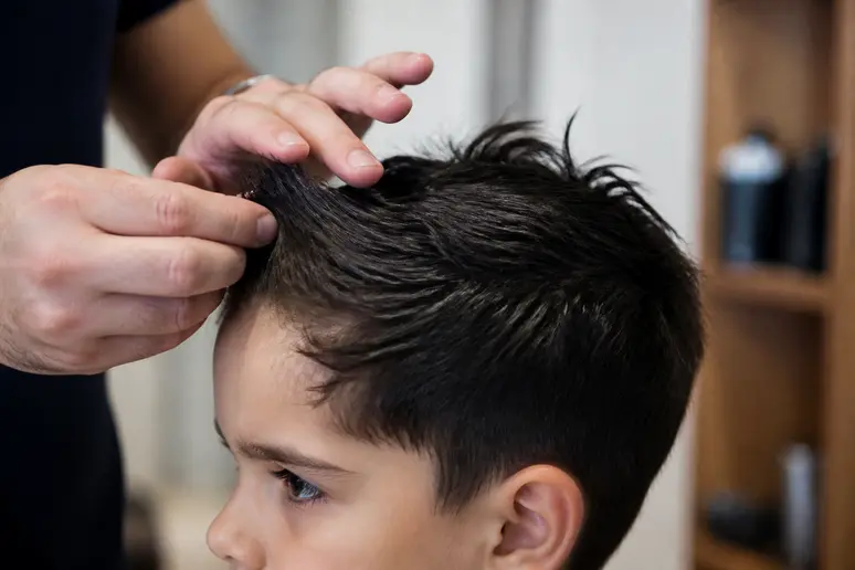 Application subtile de cire pour maîtriser les épis d'une coiffure courte garçon.
