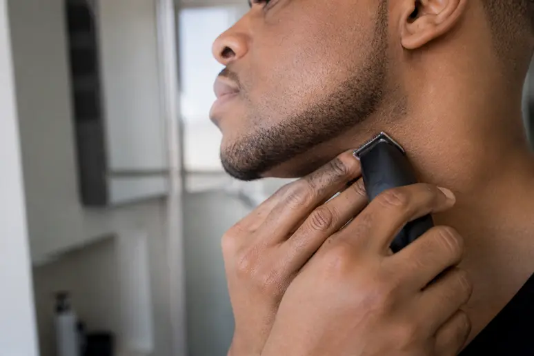 Un homme utilise une tondeuse de précision pour tailler les contours nets de son collier de barbe.