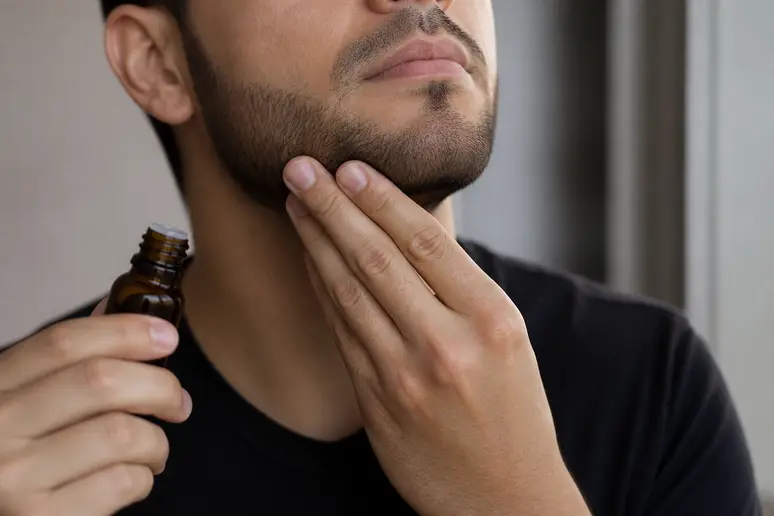 Application quotidienne d'une huile nourrissante sur un collier de barbe court et bien taillé.