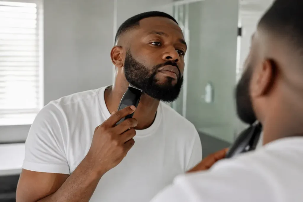 Un homme soigneusement taillé son collier de barbe devant un miroir de salle de bain lumineuse