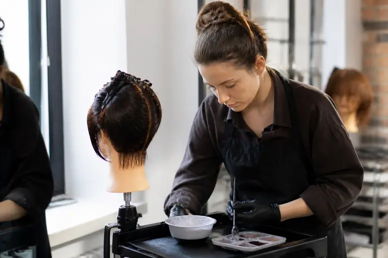 Élève en formation de coiffure s'exerçant aux techniques de coloration sur une tête d'étude