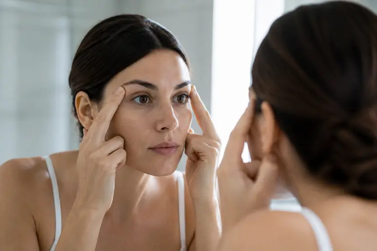 Femme observant l'écartement de ses yeux dans un miroir lumineux