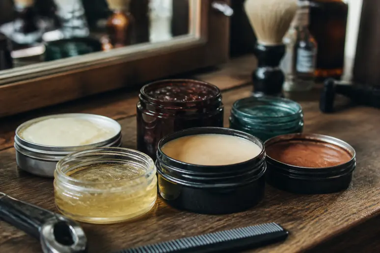Pots de pommade et de cire coiffante posés sur un meuble pour gominer les cheveux.