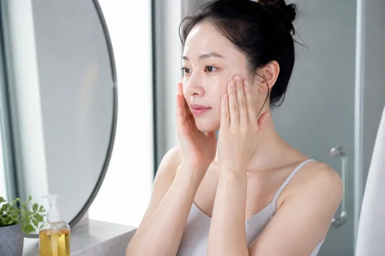 Femme appliquant une huile nettoyante, étape clé des meilleurs cosmétiques japonais.