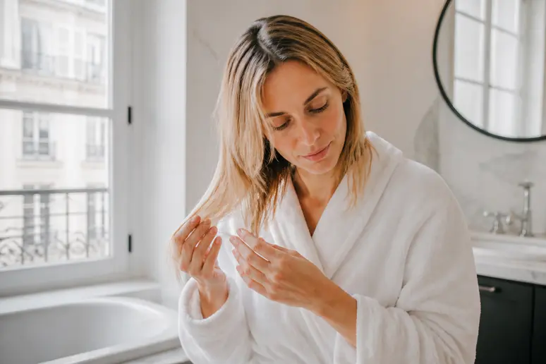 Femme parisienne appliquant un masque Olaplex avis pour cheveux abîmés, dans une salle de bain lumineuse.