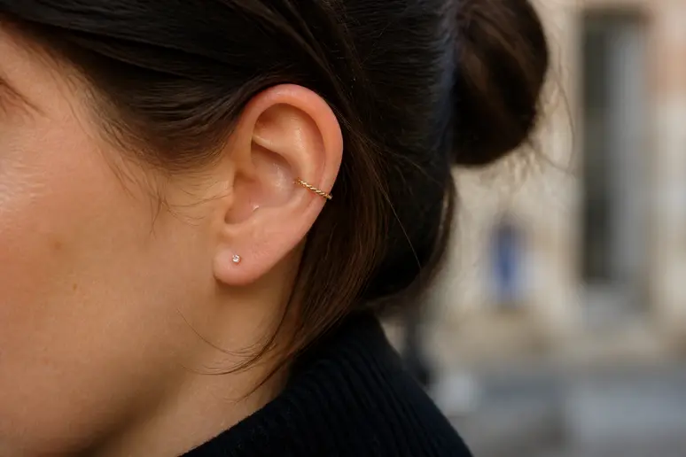 Oreille fine ornée d'un anneau discret à l'hélix et de plusieurs bijoux au lobe