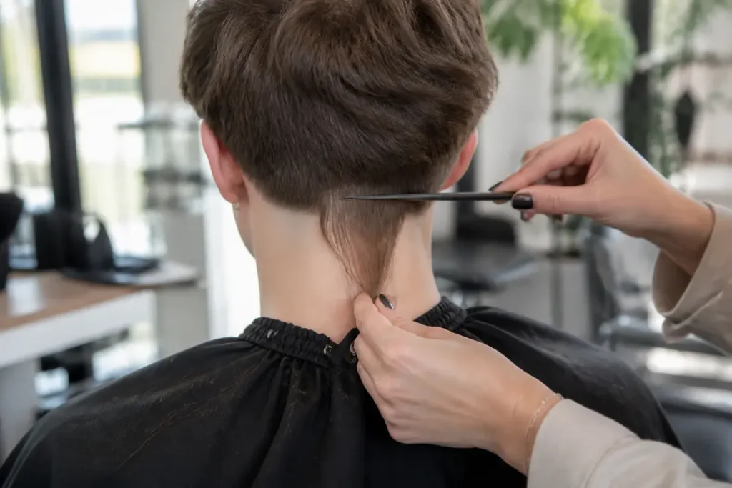 Jeune personne montrant une queue de rat coiffure originale vue de dos dans un salon moderne