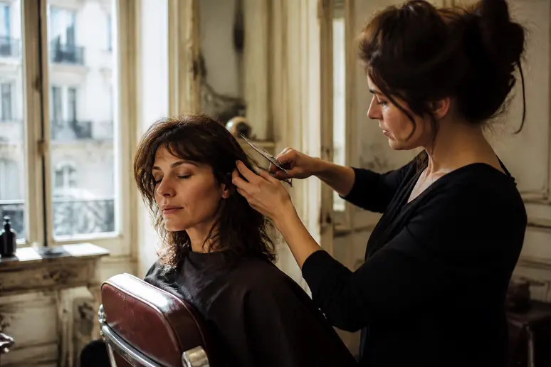 Une femme dans un salon parisien se fait couper les cheveux, symbole de transformation personnelle.