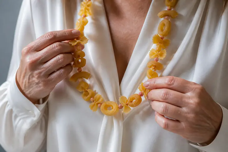 Gros plan sur un collier de nouilles original porté avec une chemise élégante