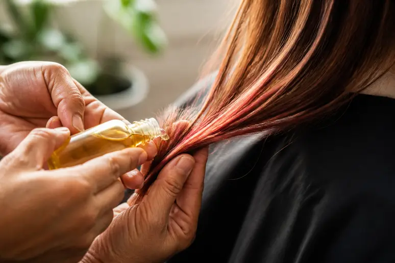 Application d'une huile protectrice sur les pointes de cheveux colorés et abîmés