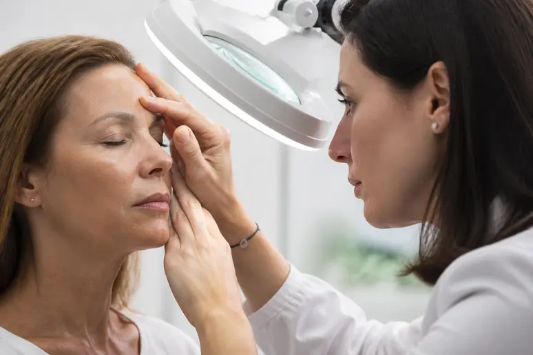 Examen dermatologique rapproché des rides glabellaires pour choisir entre toxine botulique et acide hyaluronique.