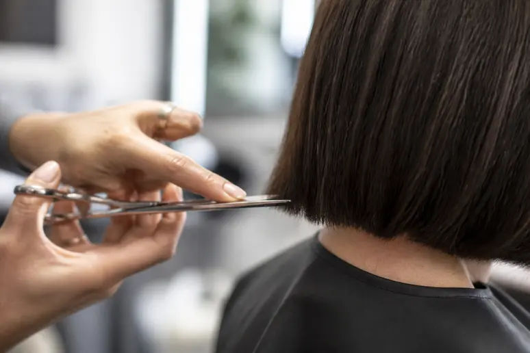 Coiffeur réalisant un piquetage léger aux ciseaux sur les pointes d'un carré court.