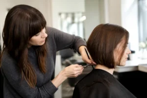 Une coiffeuse réalise une coupe skimmed bob quelle longueur parfaite dans un salon lumineux