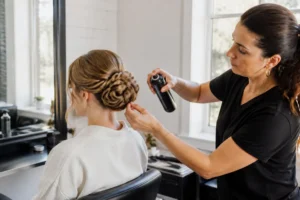 Un coiffeur professionnel réalise des tresses pour mariage soignées en salon avec des épingles et de la laque.